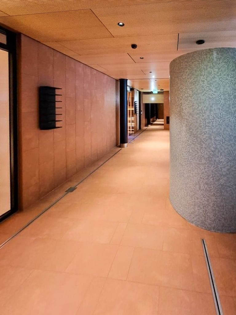 Eleganter Spa-Korridor mit grossformatigem Naturstein und Mosaiksäule