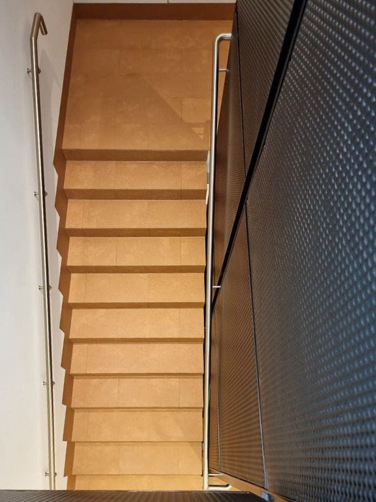 Treppe mit warmen Natursteinstufen und moderner Metallbrüstung