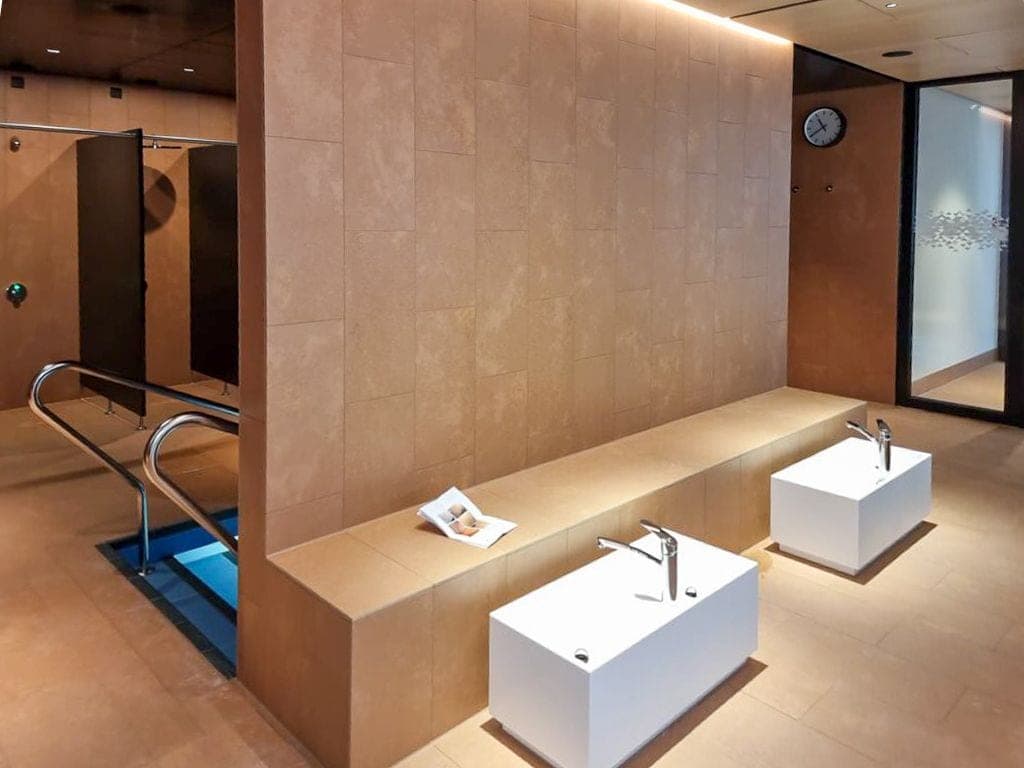 Minimalistische Waschbecken vor warmer Travertinwand im Spa-Bereich